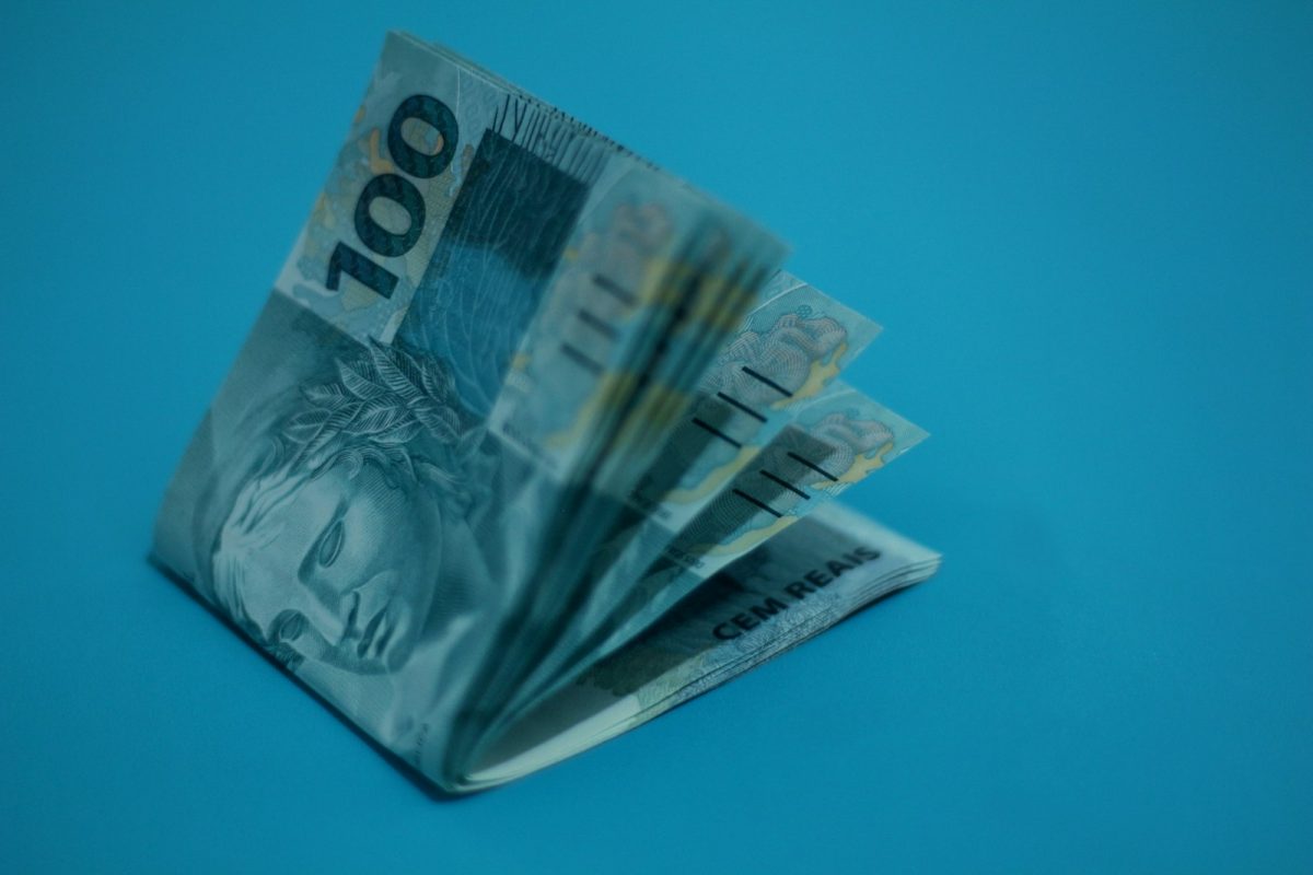 13º salário: notas de dinheiro sobre superfície azul
