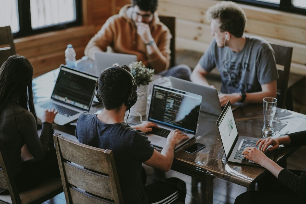 Equipe reunida em torno do laptop, rotina do analista de marketing