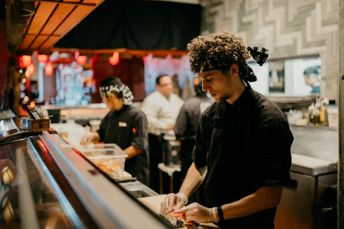 Auxiliar de cozinha trabalhando com a equipe em cozinha profissional