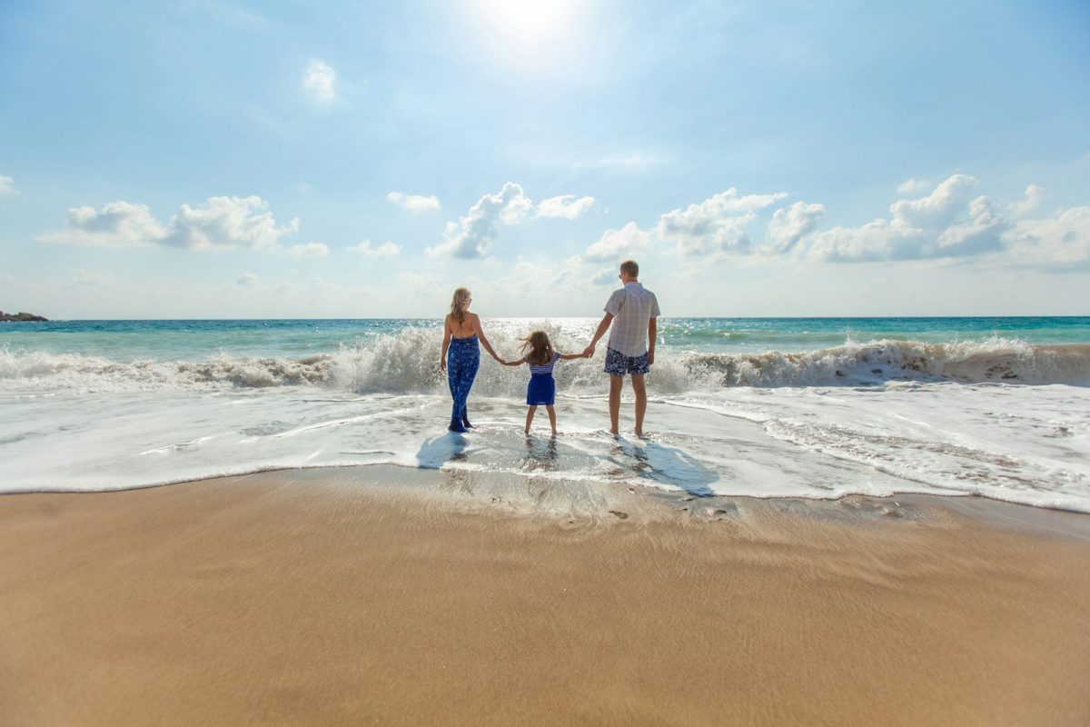 Calculadora de férias: família de mãos dadas na beira do mar