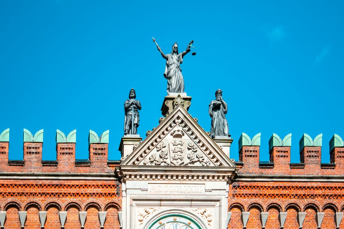 Concurso TJSP: estátua da justiça no alto de um prédio com céu azul