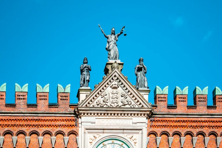 Concurso TJSP: estátua da justiça no alto de um prédio com céu azul