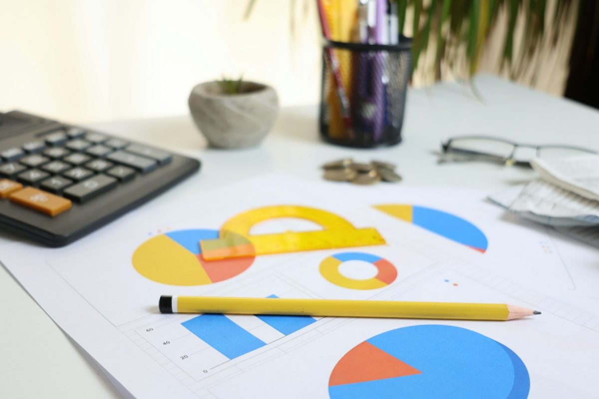 Mesa com calculadora, gráficos e lápis para revisar o controle financeiro