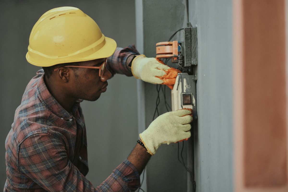 Eletricista com capacete amarelo instalando fiação elétrica