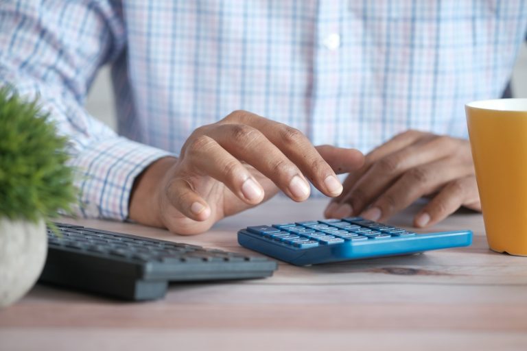 FGTS saque-aniversário: pessoa fazendo contas na calculadora ao lado de uma caneca de café