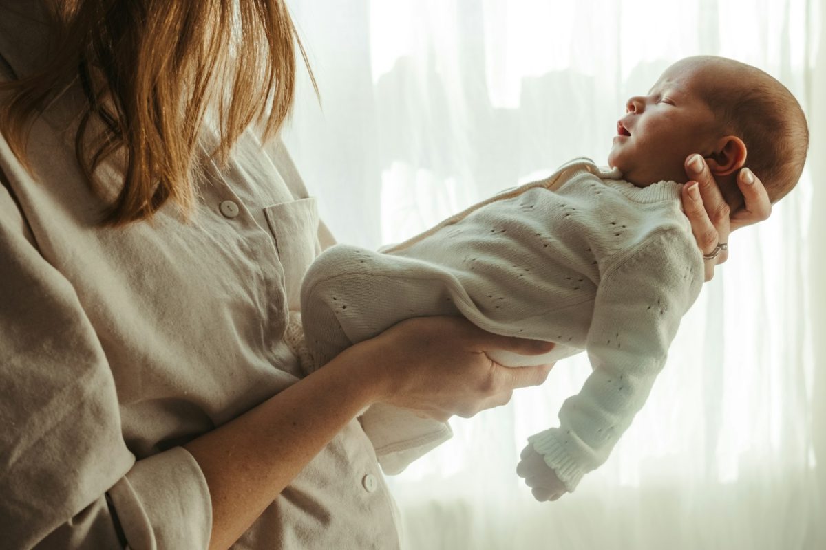 Licença-maternidade: mãe segurando o recém-nascido perto da janela