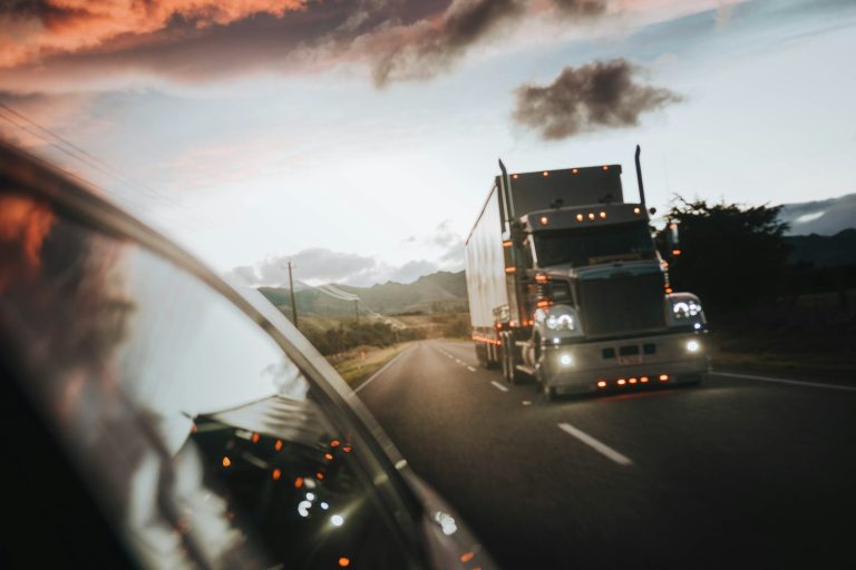 Motorista de caminhão conduz carreta em rodovia ao entardecer