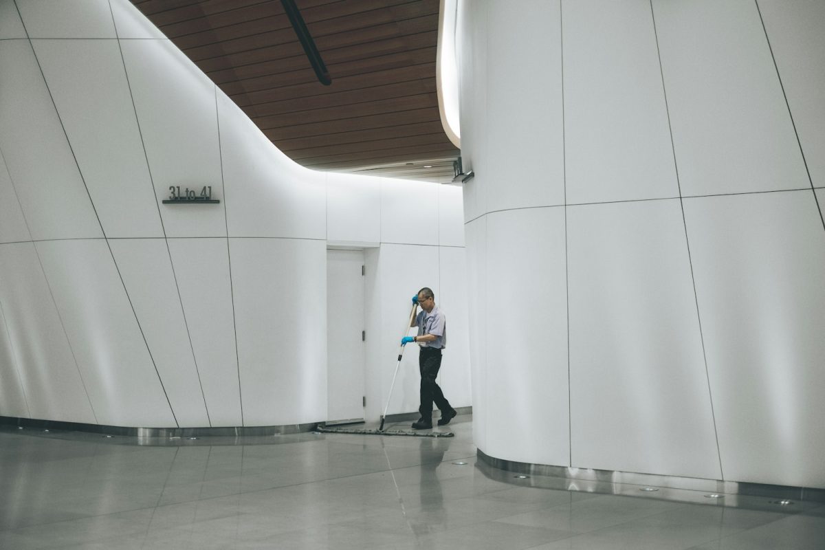 Zelador cuidando da limpeza do piso na área comum do prédio